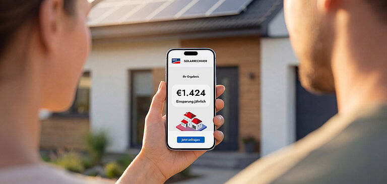 Smartphone mit SMA‑Solarrechner zeigt eine mögliche jährliche Ersparnis von 1.424 Euro vor einem Haus mit Photovoltaikanlage.