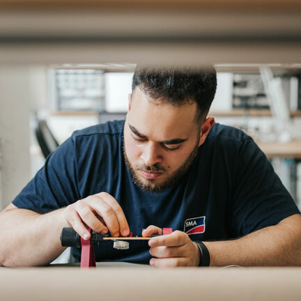 Nahaufnahme eines Auszubildenen, der an einer Platine arbeitet. 