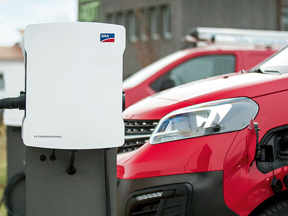 SMA EV Charger Business vor einer Reihe roter Autos auf einem Parkplatz